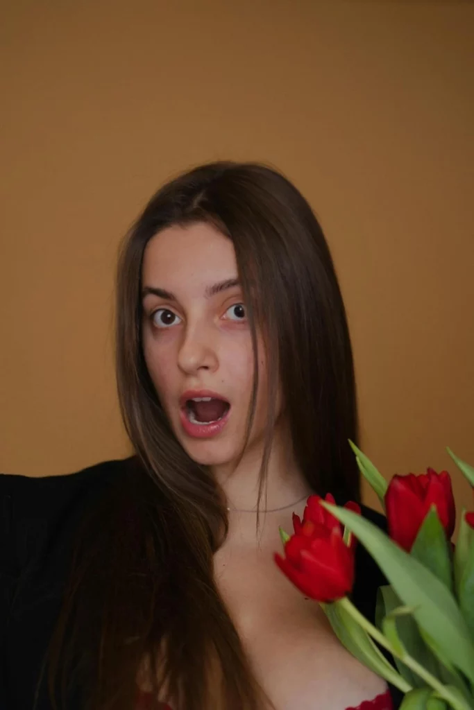 Immagine stupita di una giovane ragazza che tiene in mano dei fiori